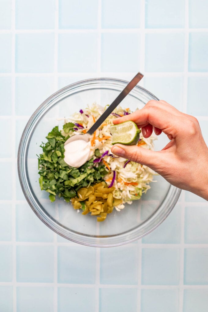 hand squeezing lime into slaw mixture